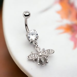 May include: Silver belly button ring with a clear crystal and a dangling bee charm. The bee is decorated with clear crystals.