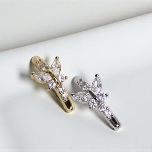 May include: Two butterfly-shaped earrings. One is gold-toned, the other silver-toned. Both earrings feature clear, sparkling crystals arranged in a butterfly design. The earrings are set against a white background.
