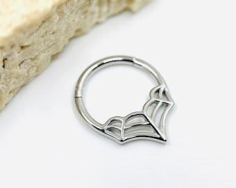 Puede incluir: Un anillo circular sin costuras de color plateado con un diseño de telaraña. El anillo está hecho de acero quirúrgico y está diseñado para piercings corporales.