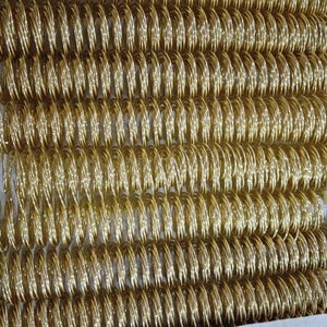 May include: A close-up of a large quantity of gold-colored metal book binding coils.