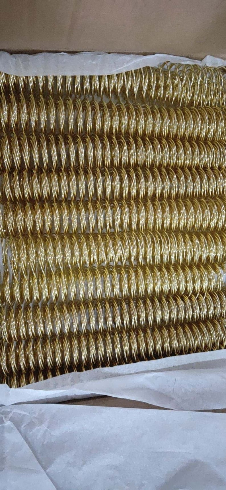 May include: A close-up of a large quantity of gold-colored metal book binding coils.