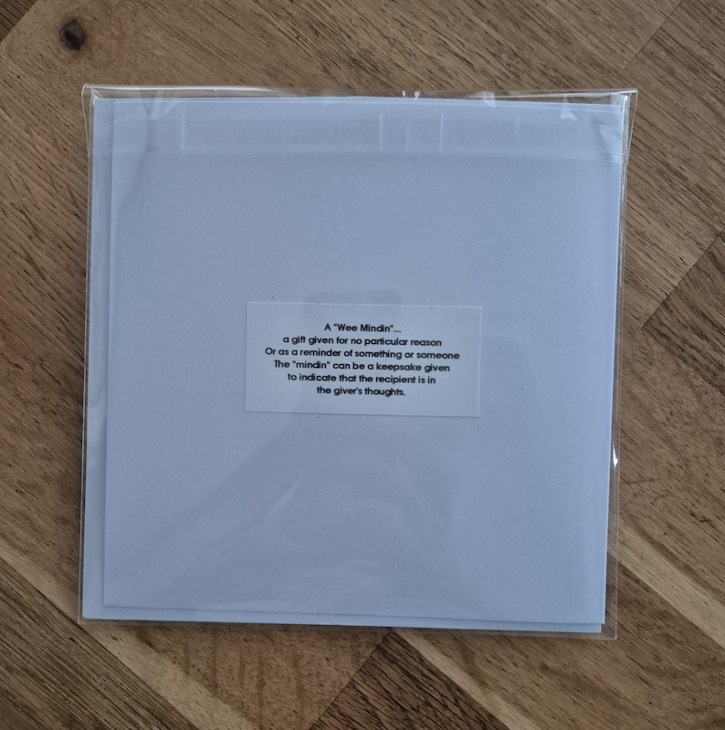 May include: A white card with a blue border and a text box that reads "A 'Wee Mindin' - a gift given for no particular reason Or as a reminder of something or someone The 'mindin' can be a keepsake given to indicate that the recipient is in the giver's thoughts."