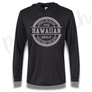 Peut inclure: Un sweat à capuche noir à manches longues avec un motif circulaire gris sur la poitrine. Le texte indique "RESPECT THE CULTURE", "HAWAIIAN", "BUILT" et "NEVER FORGET YOUR ROOTS" avec un symbole infini centré au-dessus du mot Hawaiian.