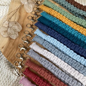 May include: A collection of colorful, braided keychains with silver key rings. The keychains are made of different colors of yarn, including red, orange, yellow, green, blue, purple, and brown.