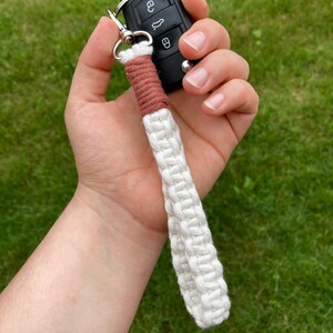 May include: A white and brown braided key chain with a black car key attached.