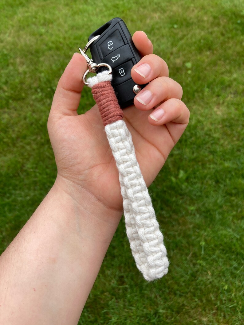 May include: A white and brown braided key chain with a black car key attached.
