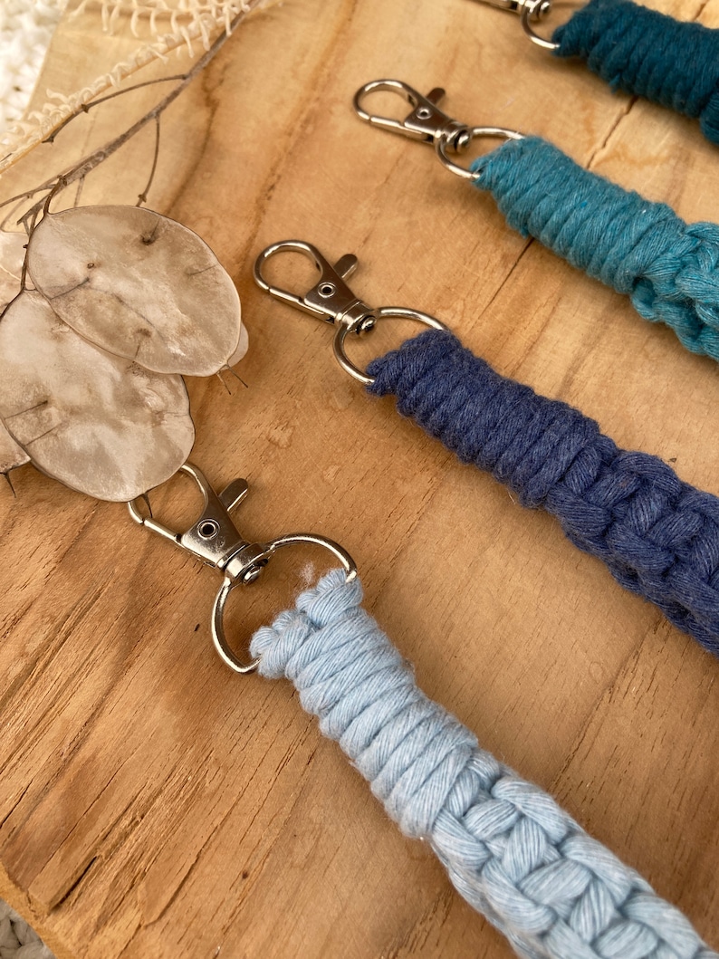 May include: Three keychains with different colored braided cords. The cords are light blue, dark blue, and teal. Each keychain has a silver metal ring and a silver metal hook.