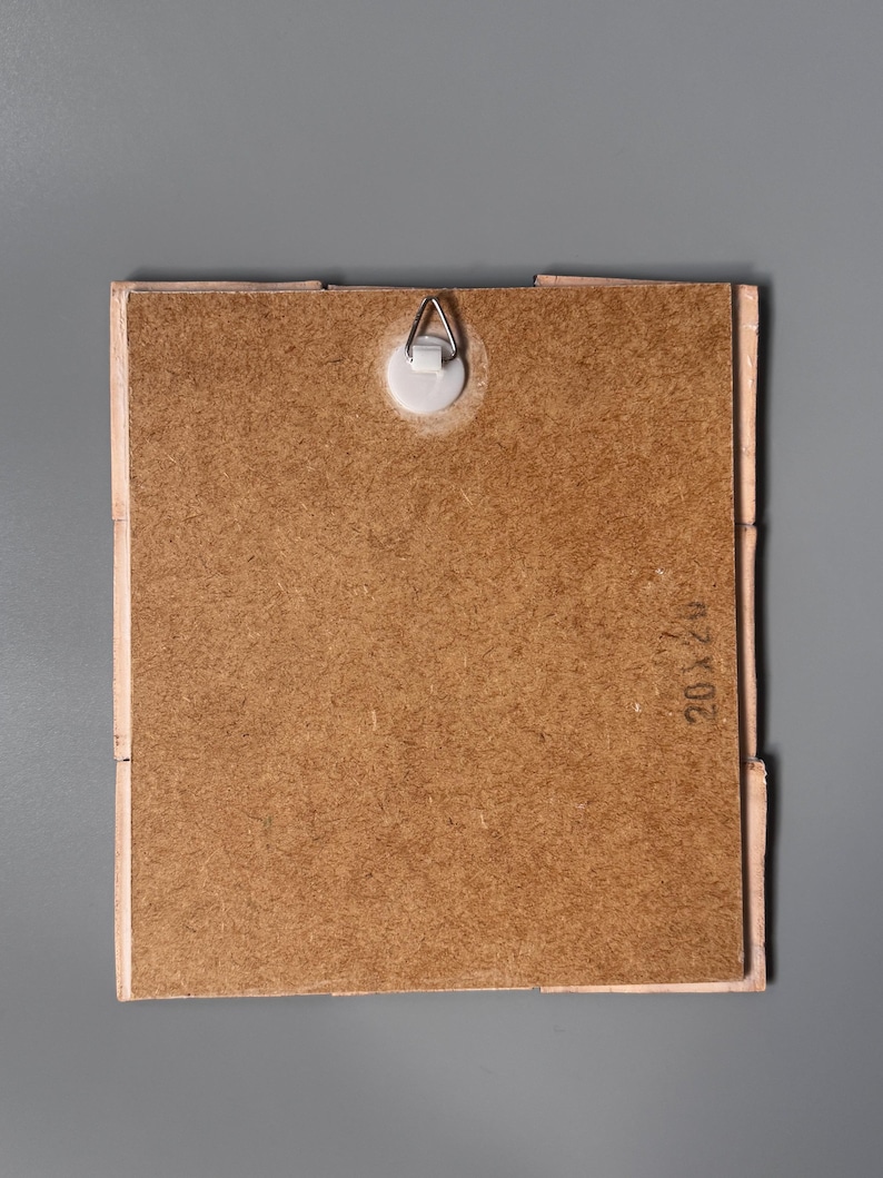 May include: A square wooden backing board with a light brown textured surface, featuring a central white plastic wall mount with a metal triangular hanger. The board has the text 20x20 stamped on the right side, indicating its dimensions.