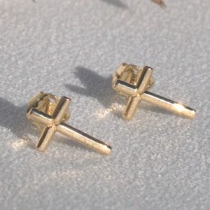May include: A pair of gold cross stud earrings. The earrings are small and delicate, and they would make a great gift for someone special.