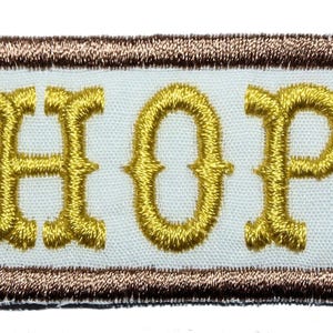 May include: A white embroidered patch with a brown border. The patch says "CHOPS" in gold lettering.