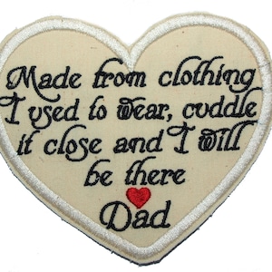 May include: A heart-shaped beige fabric patch with white stitching around the edges. The patch has black embroidered text that reads "Made from clothing I used to wear, coddle it close and I will be there Dad" with a small red heart below the text.
