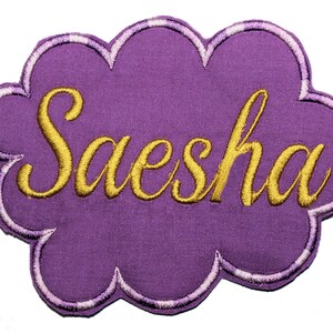 May include: Purple felt cloud-shaped patch with the name Saesha embroidered in gold thread.