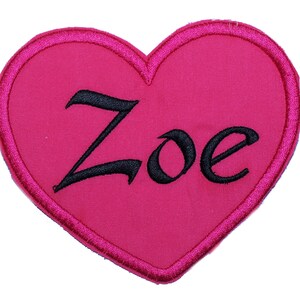May include: Pink felt heart-shaped patch with black embroidered lettering that reads "Zoe".