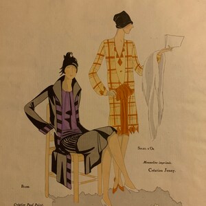 May include: Two women wearing stylish dresses and hats from the 1920s. The woman on the left is wearing a black and purple dress with a black coat and a black hat. The woman on the right is wearing a plaid dress with a white fur stole and a black hat. The text on the image reads "BLUES. Creation Paul Poiret. SOLEIL D'OR Mousseline imprim&eacute;e. Creation Jenny. Art-Go&ucirc;t-Beaut&eacute;"