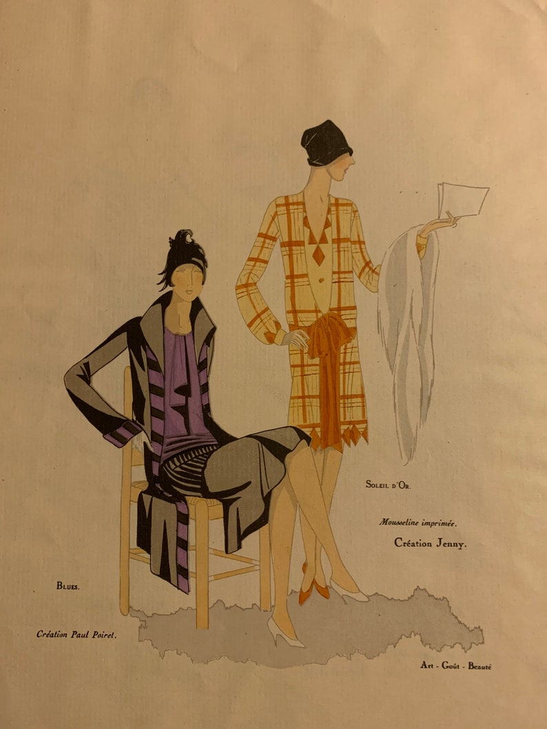 May include: Two women wearing stylish dresses and hats from the 1920s. The woman on the left is wearing a black and purple dress with a black coat and a black hat. The woman on the right is wearing a plaid dress with a white fur stole and a black hat. The text on the image reads "BLUES. Creation Paul Poiret. SOLEIL D'OR Mousseline imprim&eacute;e. Creation Jenny. Art-Go&ucirc;t-Beaut&eacute;"