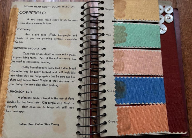 May include: A page from a color selector book showing fabric swatches in various shades of orange, peach, mint, blue, and beige. The text on the page reads "Indian Head Cloth Color Selector" and "Copperglo".