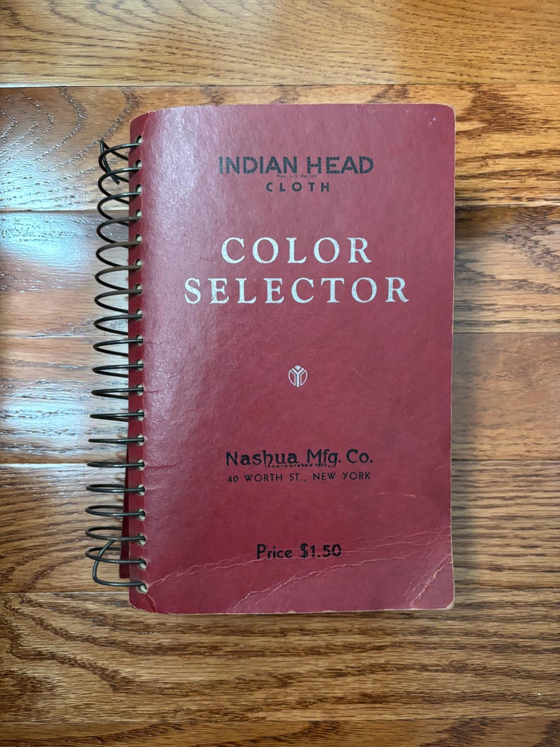 May include: A red spiral bound book with the title "INDIAN HEAD CLOTH COLOR SELECTOR" and the text "Nashua Mfg. Co. 40 WORTH ST., NEW YORK" and "Price $1.50".