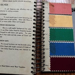 May include: A page from a fabric color guide book showing swatches of different colors. The colors are labeled with names like "Coral", "Sungold", "Turf", "Cadet", and "Wine". The text on the page says "Indian Head Cloth Color Selector" and "Indian Head Colors never "Run" Together."