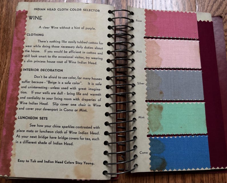 May include: A page from a vintage fabric color selector book. The page features the color "Wine" and shows swatches of different colors, including Rose, Pink, Silver, Mint, and Como. The text on the page describes the color Wine and suggests ways to use it in clothing, interior decoration, and luncheon sets.