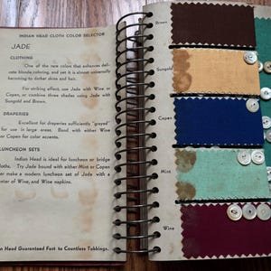 May include: A color selector guide for Indian Head cloth, featuring swatches of fabric in various colors, including jade, brown, sungold, copen, mint, and wine. The guide includes text describing the uses and properties of each color.