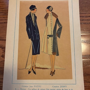 May include: Vintage fashion illustration from 1925, featuring two women in stylish outfits. One wears a navy blue suit with a hat and cane, the other a cream-colored coat with a contrasting collar. The image has text in French.