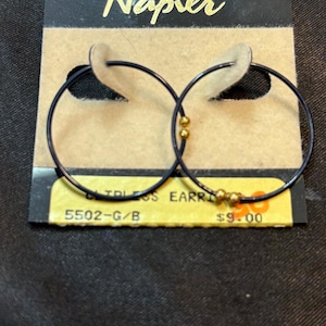 May include: Black hoop earrings with gold-colored beads, displayed on a Napier branded tag. The earrings are circular with a dark finish and small gold accents. The tag has the text "Napier" in gold.
