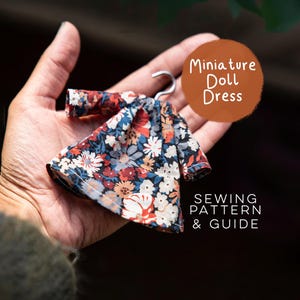 Könnte beinhalten: Ein Miniatur-Puppenkleid mit einem dunklen Blumenmuster aus roten, weißen und blauen Blüten auf schwarzem Grund, das an einem kleinen Metallbügel hängt. Der Text auf dem Bild lautet Miniature Doll Dress SEWING PATTERN & GUIDE.