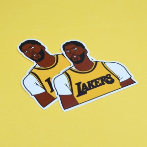 Puede incluir: Dos pegatinas de un jugador de baloncesto que lleva una camiseta amarilla con la palabra "LAKERS" en la parte delantera. El jugador mira hacia la derecha y tiene una expresi&oacute;n seria en su rostro.