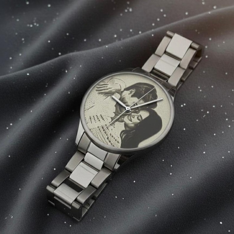 K&ouml;nnte beinhalten: Silberfarbene Armbanduhr mit einem Schwarz-Wei&szlig;-Foto eines Paares auf dem Zifferblatt. Die Uhr hat ein Metallarmband und ein rundes Zifferblatt. Das Foto zeigt ein sich umarmendes Paar.