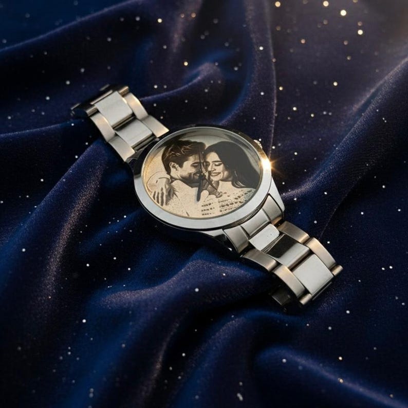 May include: A silver wristwatch with a stainless steel band. The watch face features a black and white image of a couple embracing. The watch is displayed on a dark blue, star-speckled fabric.