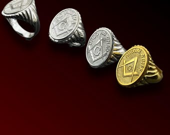 May include: Four silver and gold Masonic rings with different designs. The rings feature a compass and square, a letter G, and the words "Ordo Ab Chao" and "Hiram Abif".