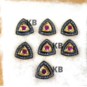 Peut inclure: Six boucles d'oreilles triangulaires avec un sertissage en argent oxydé noir et une seule pierre de rubis au centre de chaque boucle d'oreille. Les boucles d'oreilles sont entourées d'une rangée de petits diamants.