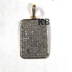 May include: A silver pendant with a rectangular shape, completely covered in small, white diamonds. The pendant has a gold bail.