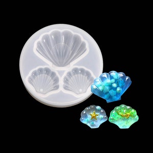 May include: A clear silicone mould with three seashell shapes. The mould is used to create resin jewellery. Three seashells are shown filled with resin and glitter.