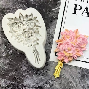 May include: A white silicone mould shaped like a bouquet of roses. The mould is used to create edible decorations for cakes and other desserts.