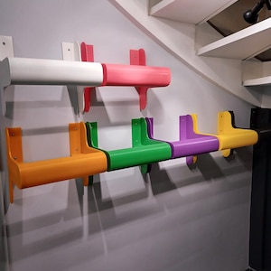 Op de afbeelding: Een set van zes kleurrijke wandplanken, elk in een andere kleur: oranje, groen, paars, geel, roze en wit. De planken zijn gemaakt van stevig plastic en zijn ontworpen om kleine voorwerpen te dragen.