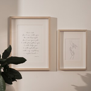 May include: Two framed prints, one with a black and white line drawing of two hands reaching towards each other, and the other with a quote from Isaiah 41:10, "Fear not, for I am with you; be not dismayed, for I am your God. I will strengthen you and help you; I will uphold you with my righteous right hand."