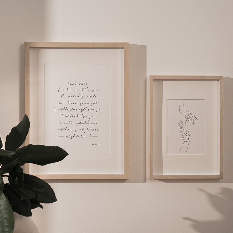 May include: Two framed prints, one with a black and white line drawing of two hands reaching towards each other, and the other with a quote from Isaiah 41:10, "Fear not, for I am with you; be not dismayed, for I am your God. I will strengthen you and help you; I will uphold you with my righteous right hand."