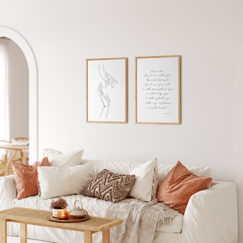 May include: Two framed prints on a white wall. The print on the left is a line drawing of two hands reaching towards each other. The print on the right has a quote from the Bible, Isaiah 41:10, "Fear not, for I am with you; I will strengthen you; I will help you; I will uphold you with my righteous right hand."