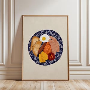 Puede incluir: Impresión enmarcada de un desayuno inglés completo en un plato azul floral. El desayuno incluye huevos fritos, tocino, frijoles, salchichas, tostadas y una rodaja de tomate. La impresión se muestra contra una pared neutra y un suelo de madera.