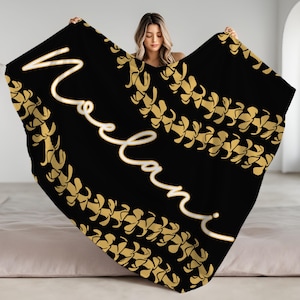 May include: Black throw blanket with a gold floral pattern and the name "Noelani" written in white cursive.