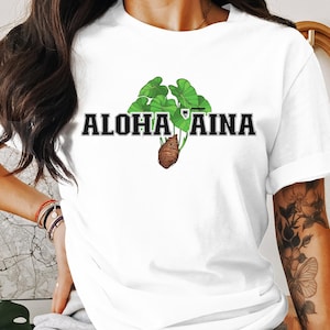May include: White t-shirt with a green plant graphic and the text "ALOHA 'AINA" in black.