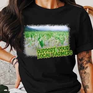 May include: Black t-shirt with a green and white graphic of a field of plants and the text "Support Your Local Farmers".