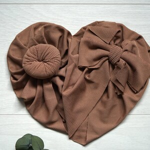 May include: Two brown ribbed fabric headbands, one tied in a bow and the other with a bun-shaped center.