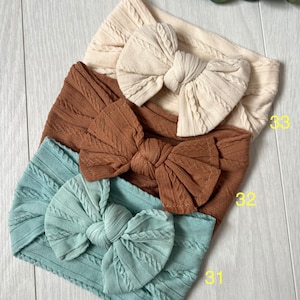 Op de afbeelding: Drie stoffen hoofdbanden met een geknoopt strikdesign. De hoofdbanden zijn in de kleuren bruin, beige en lichtblauw. De nummers 31, 32 en 33 staan op de afbeelding.