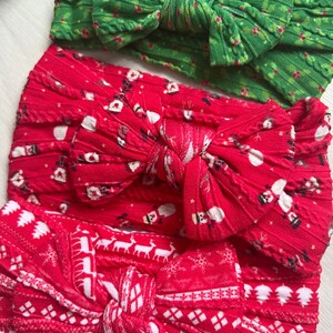 Op de afbeelding: Drie kerstthema hoofdbanden met rode en groene stof. De hoofdbanden zijn gebonden in een strik en hebben verschillende patronen, waaronder sneeuwvlokken, rendieren en hulst.