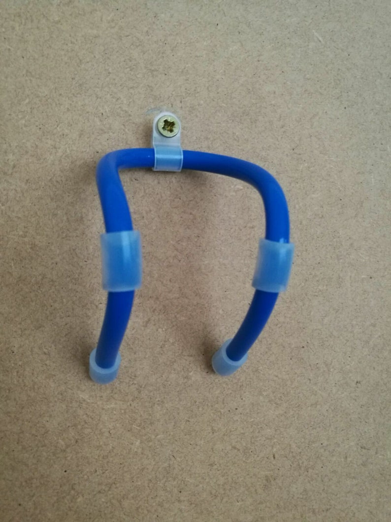 K&ouml;nnte beinhalten: Ein blauer, U-f&ouml;rmiger Wandhalter mit transparenten Kunststoffclips und Endkappen. Der Halter ist mit einer Schraube an einer hellbraunen Oberfl&auml;che befestigt.