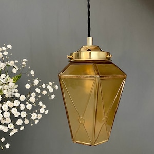 Lámpara colgante vintage estilo art déco con forma de globo en cristal amarillo y dorado.