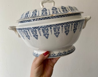 Puede incluir: Un tazón de servir de cerámica blanca con un patrón floral azul y blanco. El tazón tiene una tapa y dos asas.