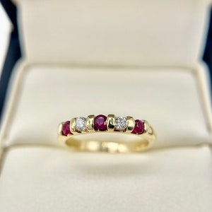 May include: A gold band ring with alternating red rubies and white diamonds.